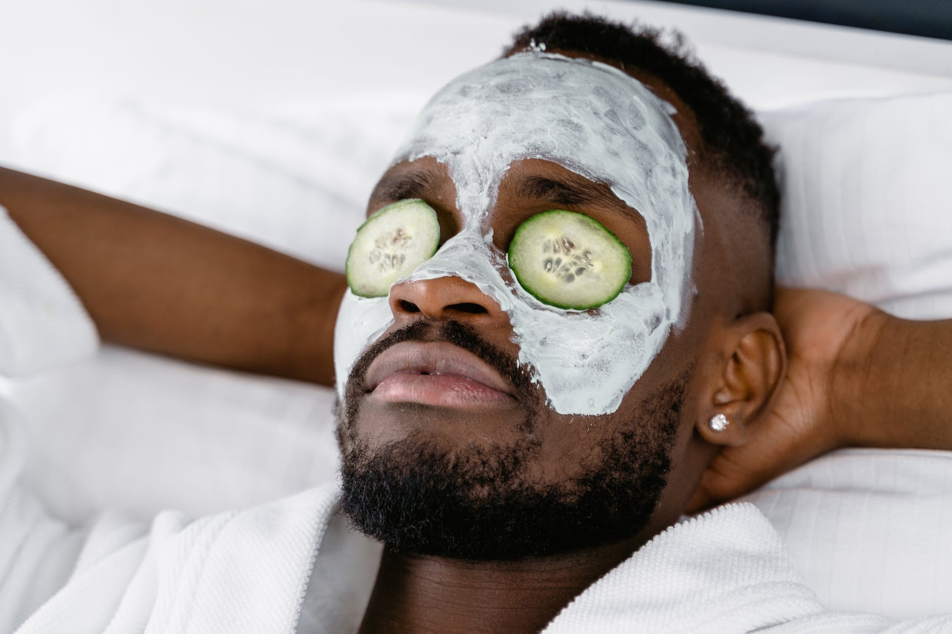 a man relaxing with cream on his face and cucumber slices in his eyes